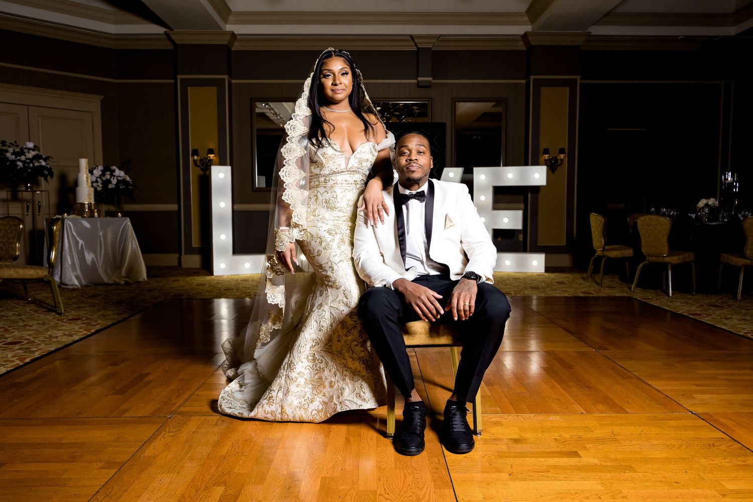 An elegant wedding photo featuring a couple posing on a hardwood floor in formal attire.