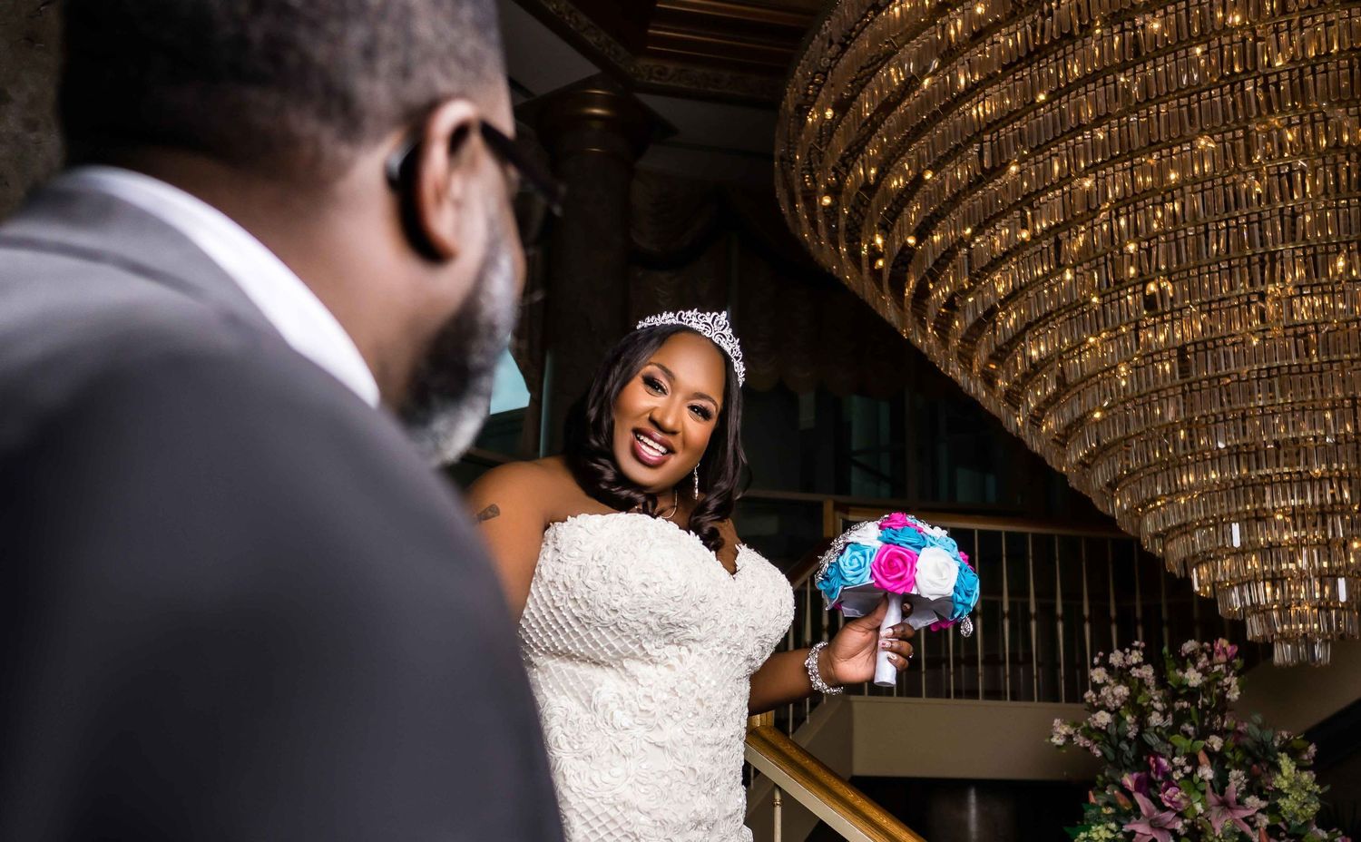 Joyful moment captured under ornate chandelier during wedding celebration.