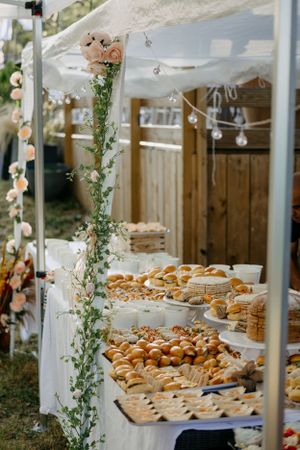 Wedding dessert table display with assorted pastries and greenery decorations.