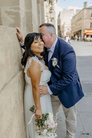 A couple shares intimate moments against an ornate stone wall during their wedding shoot.