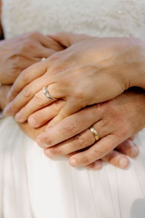 Close-up sequence of hands with wedding rings against white fabric background.