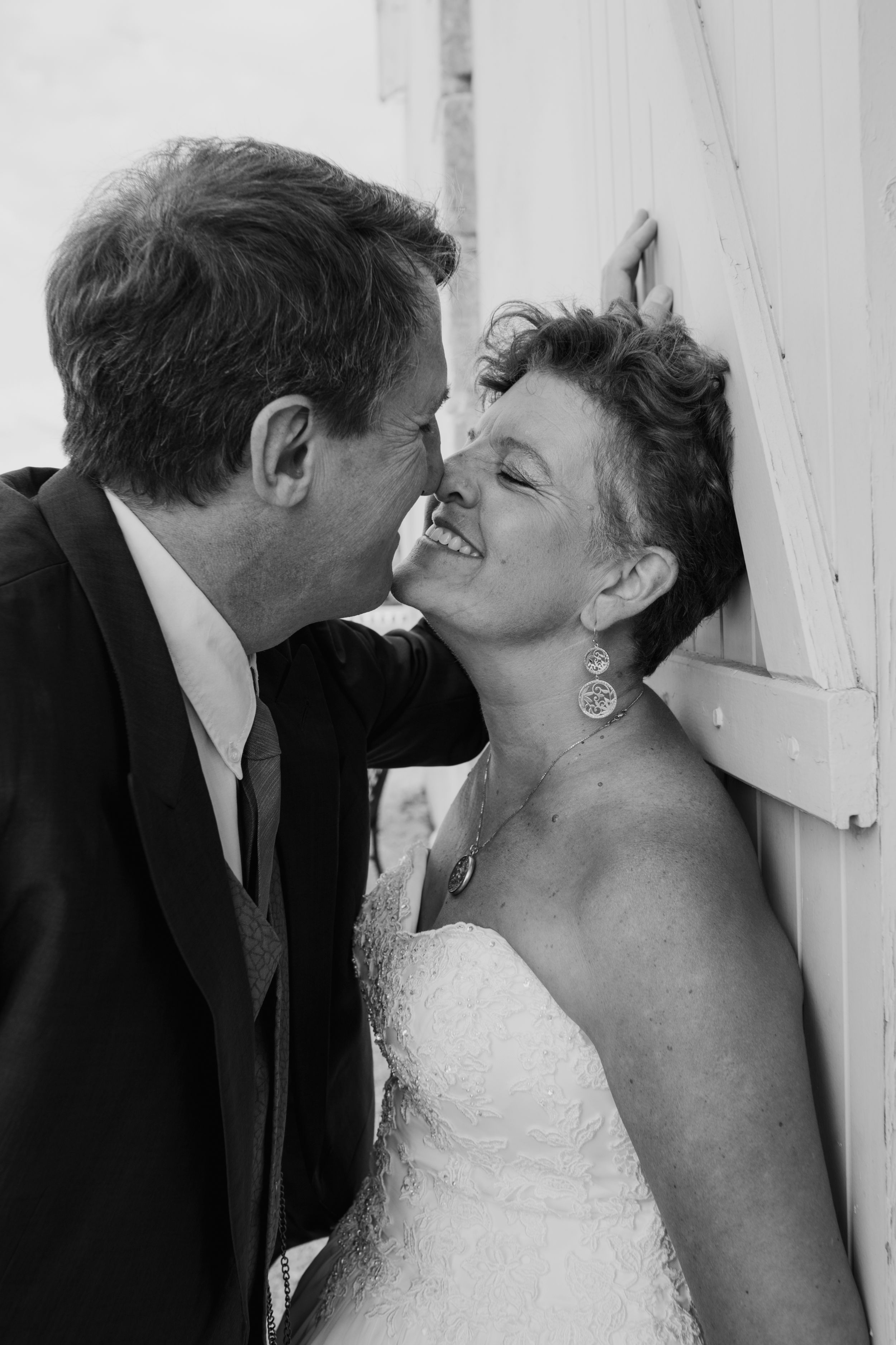 Intimate black and white wedding portraits against white wooden shutters.