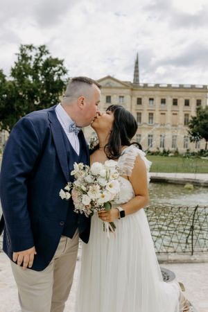A wedding couple shares romantic moments outside a grand historic building.