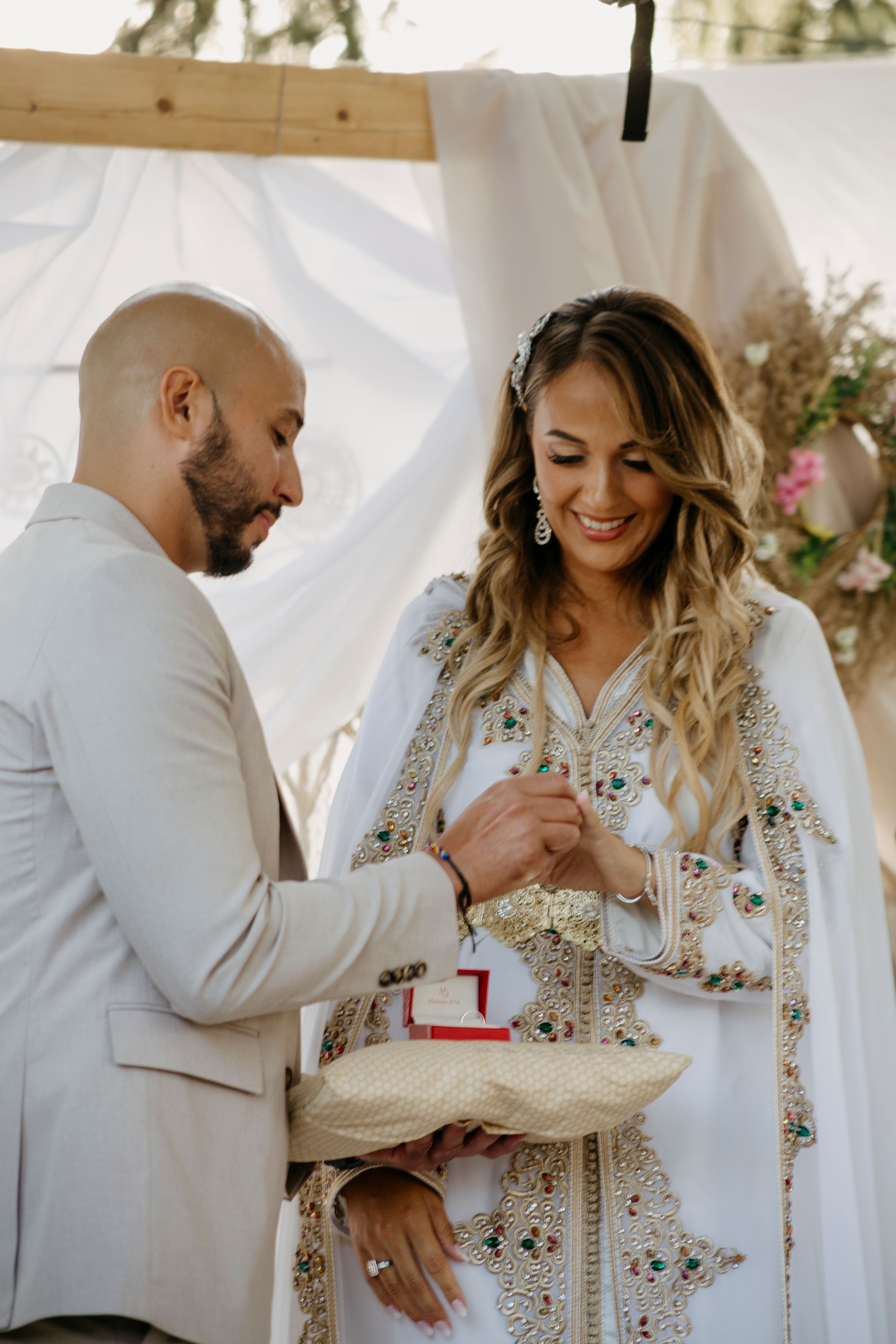 A couple shares an intimate moment during their wedding ceremony under a white canopy.