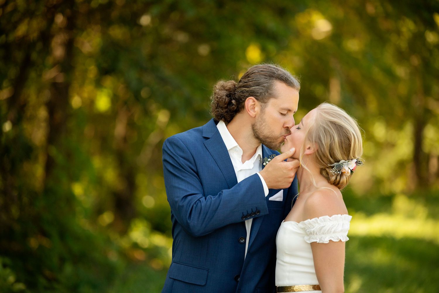 A romantic wedding kiss between newlyweds in a garden setting with soft natural lighting.