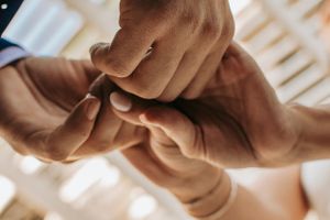 Close-up shot of hands joining together during a wedding ceremony moment.