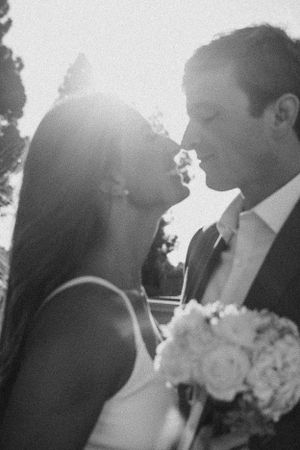 Black and white romantic portrait of a couple with a bridal bouquet in soft sunlight.