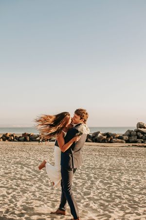 A romantic beach photoshoot with a couple spinning and dancing in the sunset light.