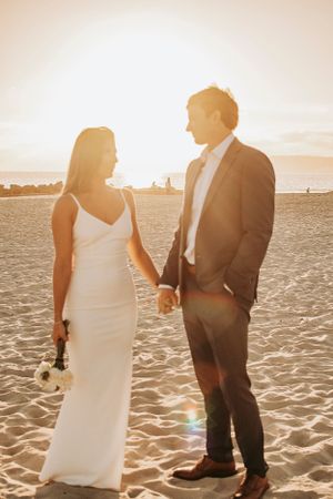 A couple shares an intimate moment on the beach during golden hour.