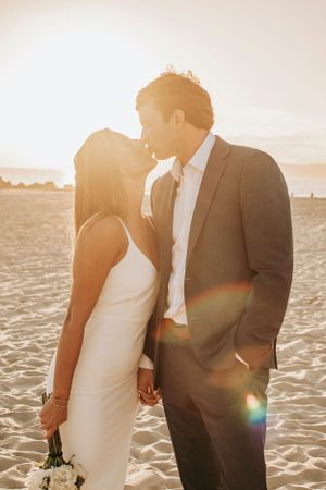 A romantic sunset beach moment between newlyweds with beautiful lens flare.