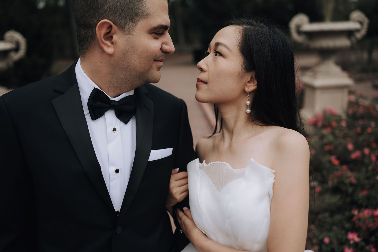 An intimate wedding portrait captured in a garden setting with blooming roses.
