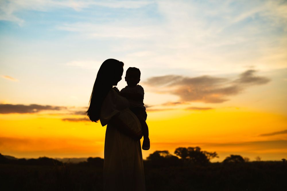 Silhouette of figures against vibrant orange and yellow sunset sky.
