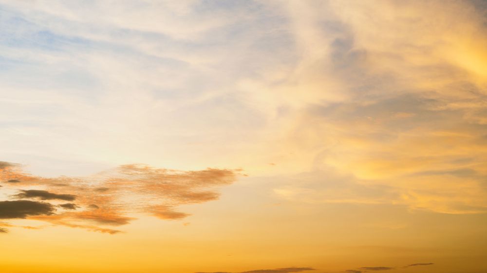 Dramatic golden sunset sky with wispy clouds creating warm atmospheric lighting.