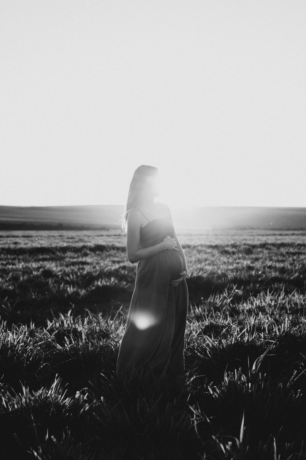 Silhouette of a figure standing in a misty field at sunset.