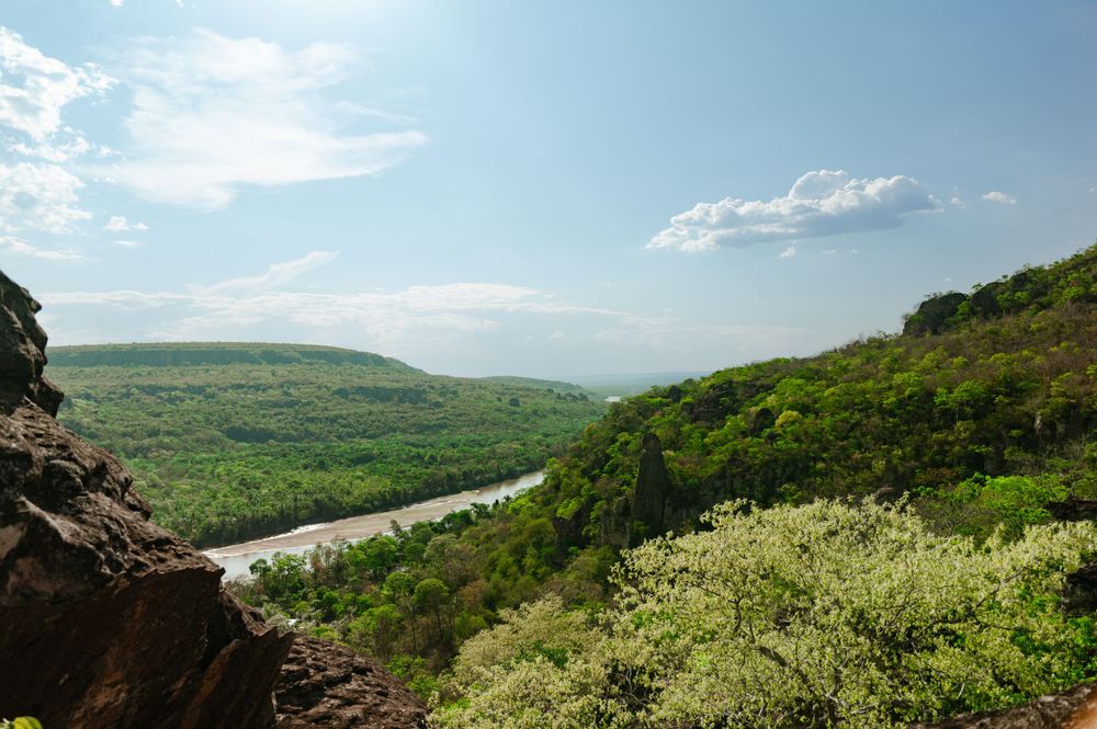 Scenic overlook of a winding river valley with lush green hills and blue sky.