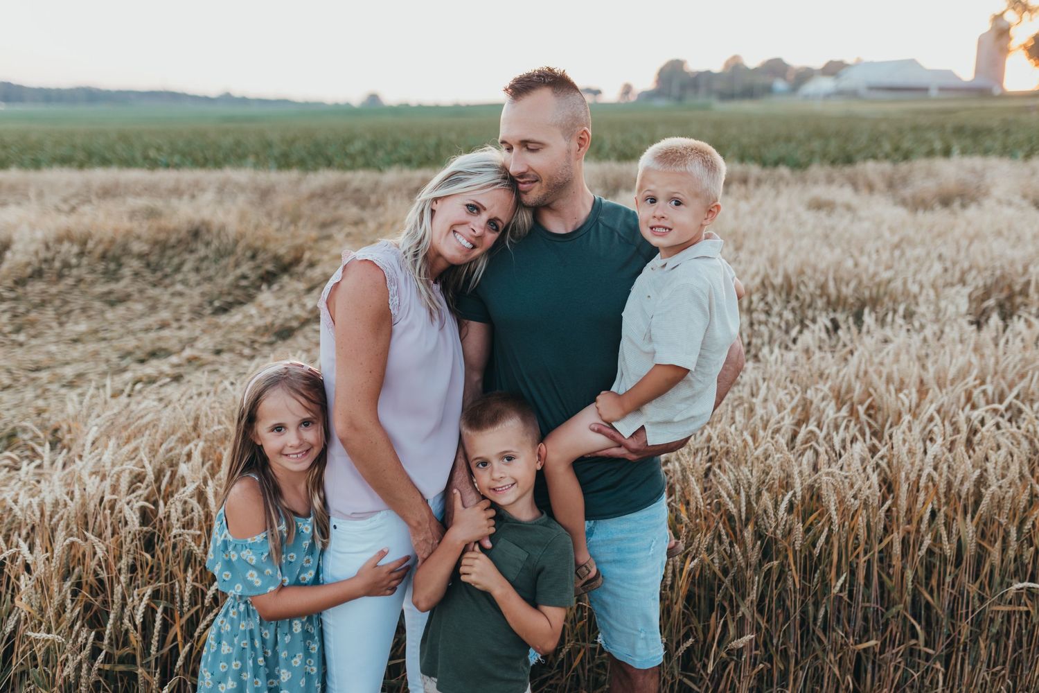 A family stands in front of a wheat field at sunset for their family photo session in Lancaster PA
