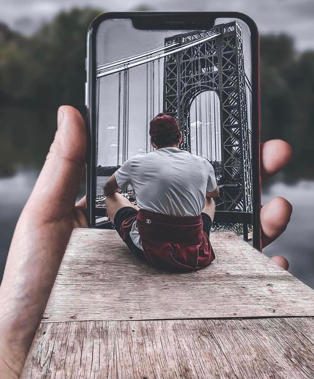 A sequence of hands holding and manipulating a small photography print against a wooden surface.