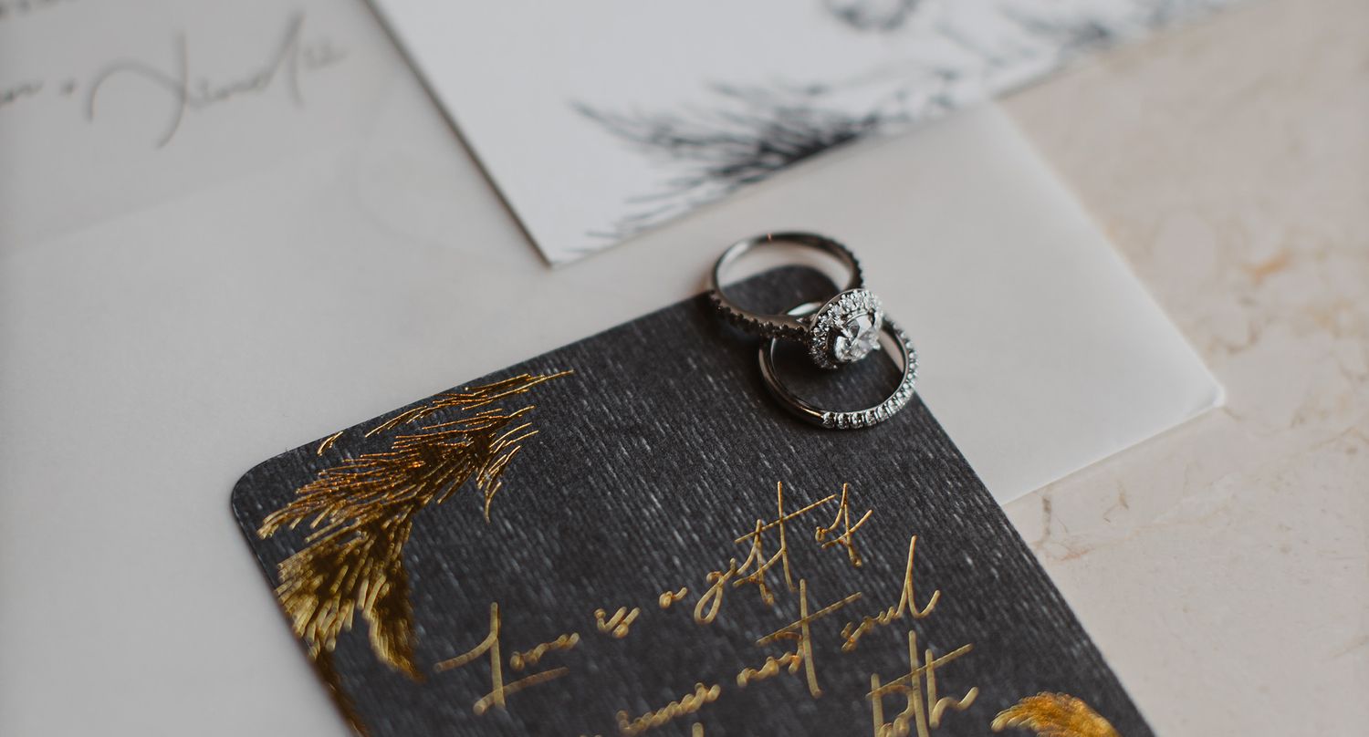 wedding rings on top of wedding invitation card