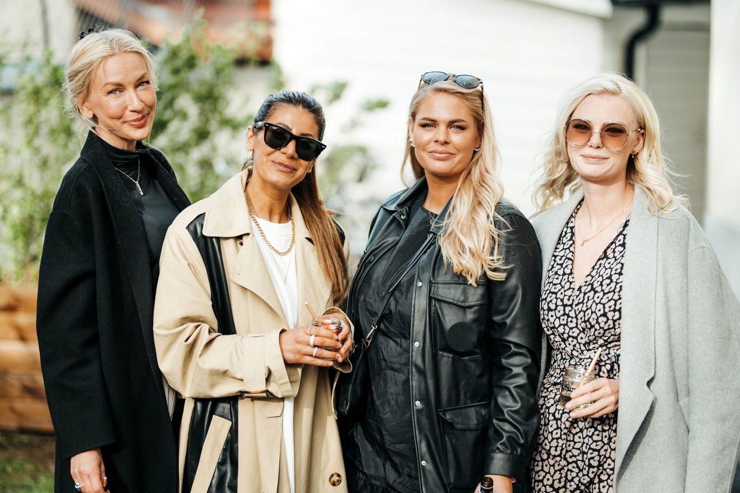Four friends posing outdoors in stylish winter coats and sunglasses.