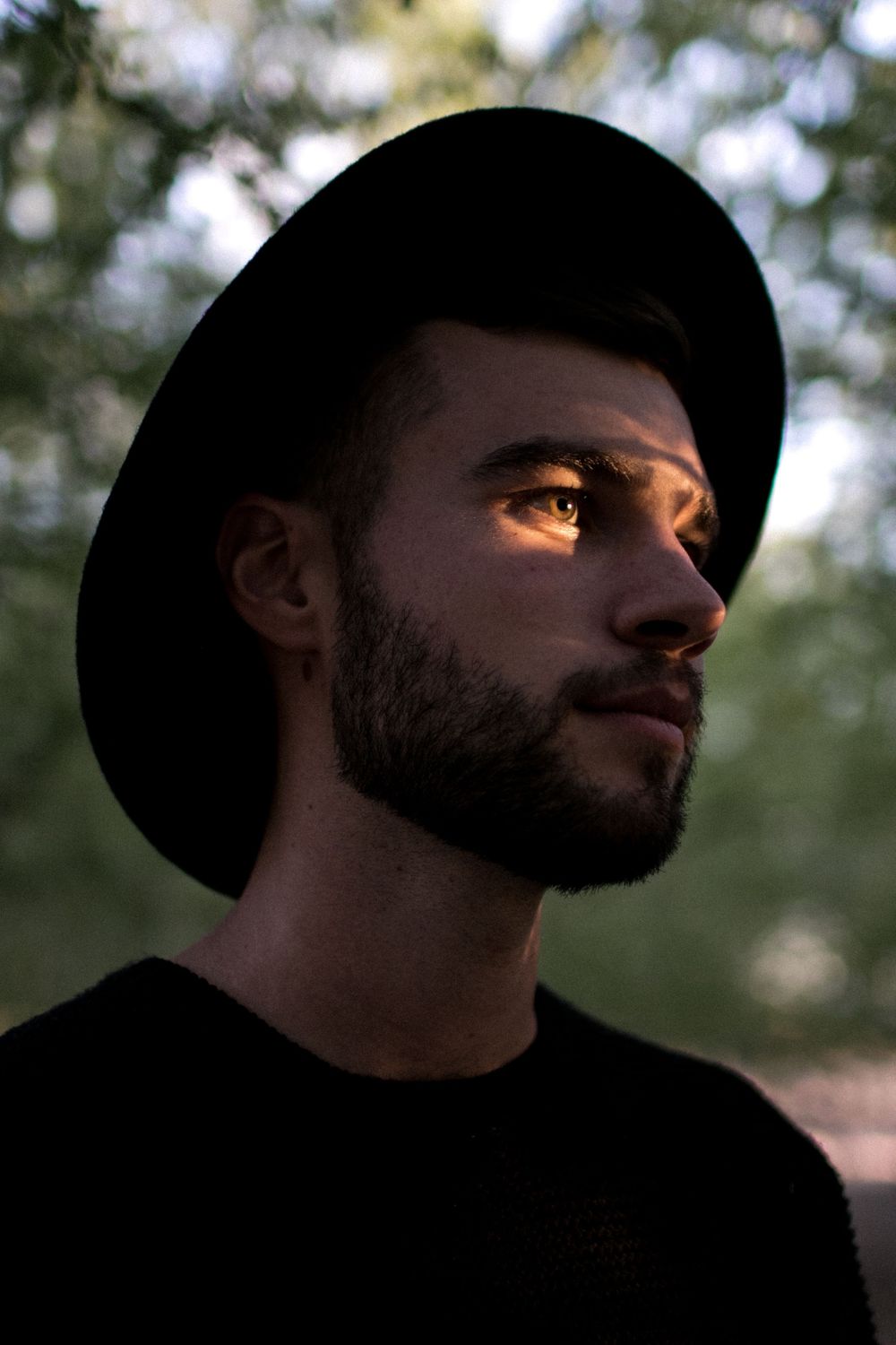 Silhouette profile of a person in a black hat during golden hour.