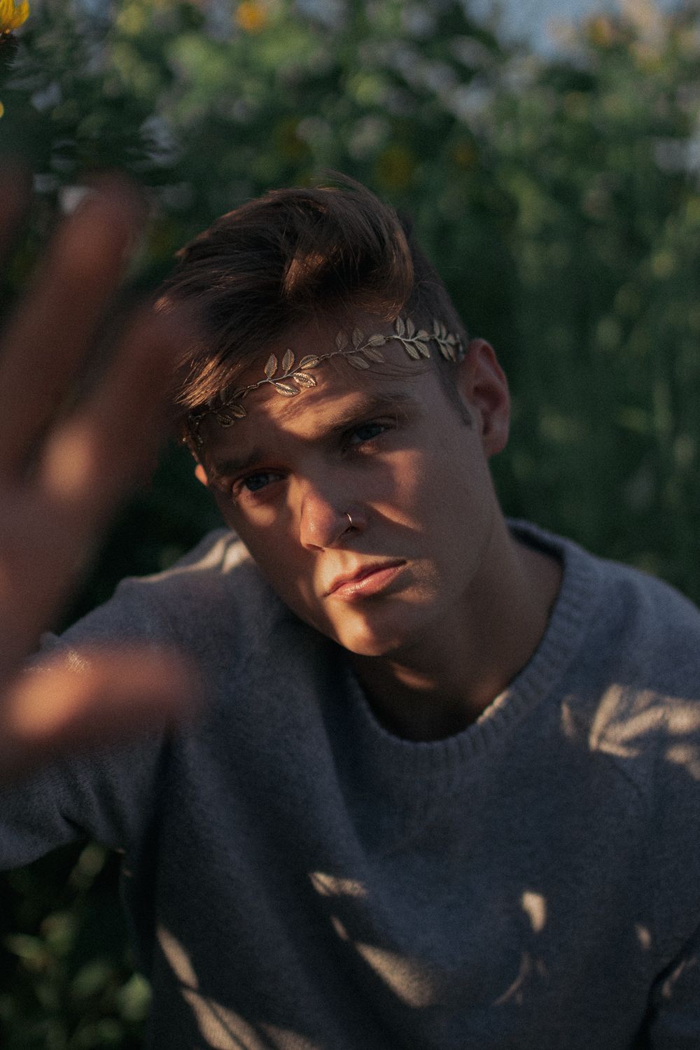 Moody portrait with botanical crown accessory in golden hour lighting.