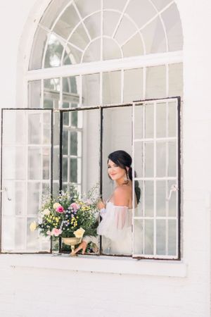 bride looking out window holding bouquet