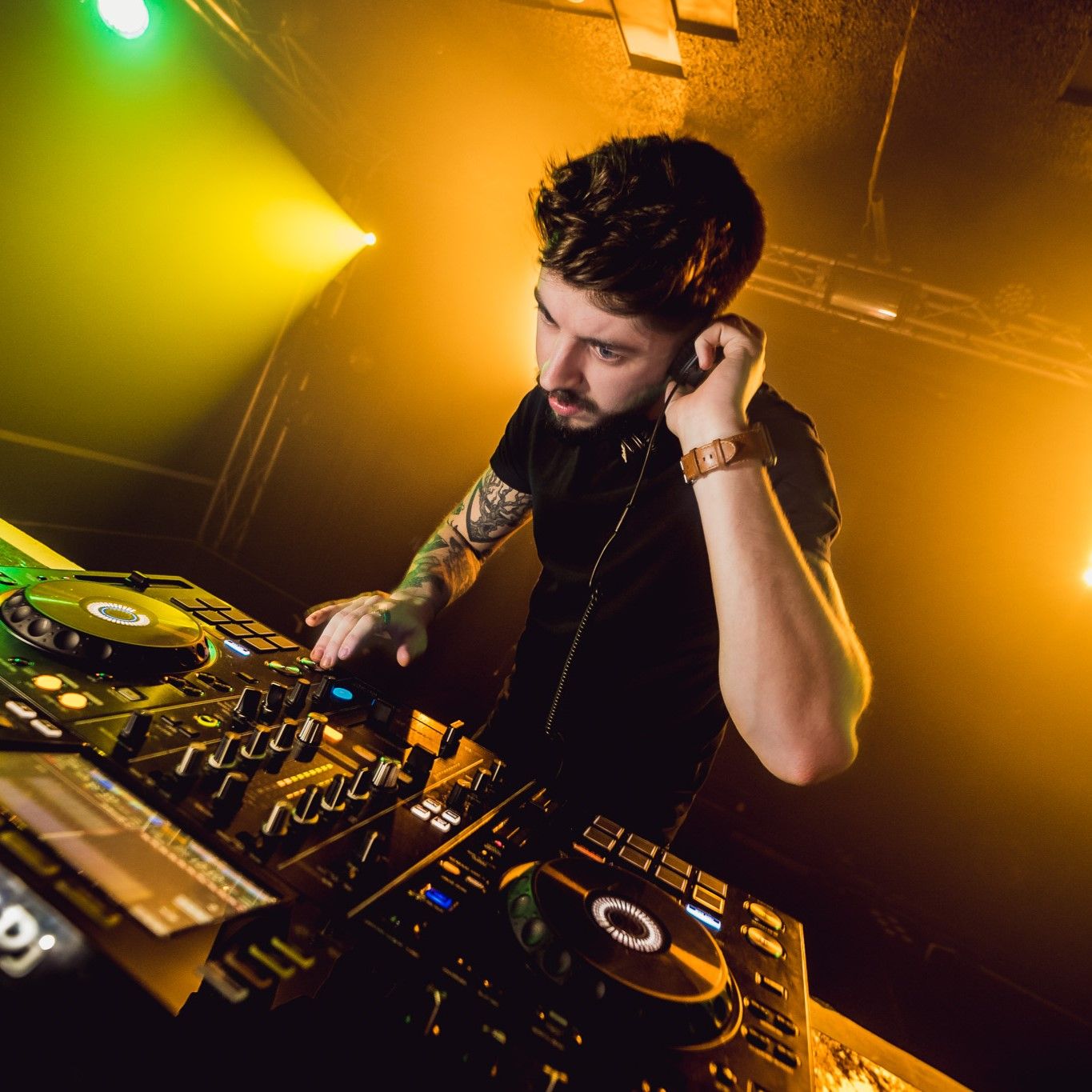 DJ mixing at turntables with colourful yellow and green stage lighting, nightclub live event photography Southampton