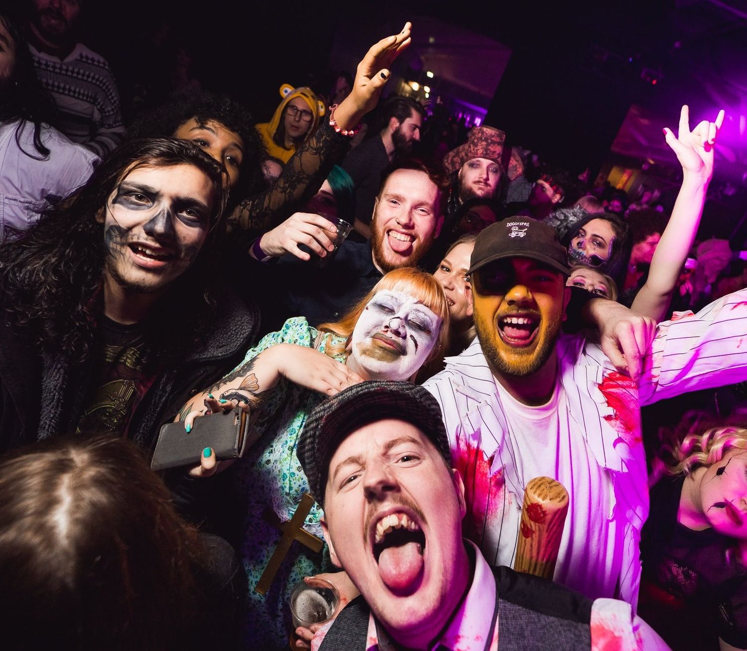 Group of friends cheering and posing at a nightclub party with purple and pink lighting, nightlife event photography Southampton