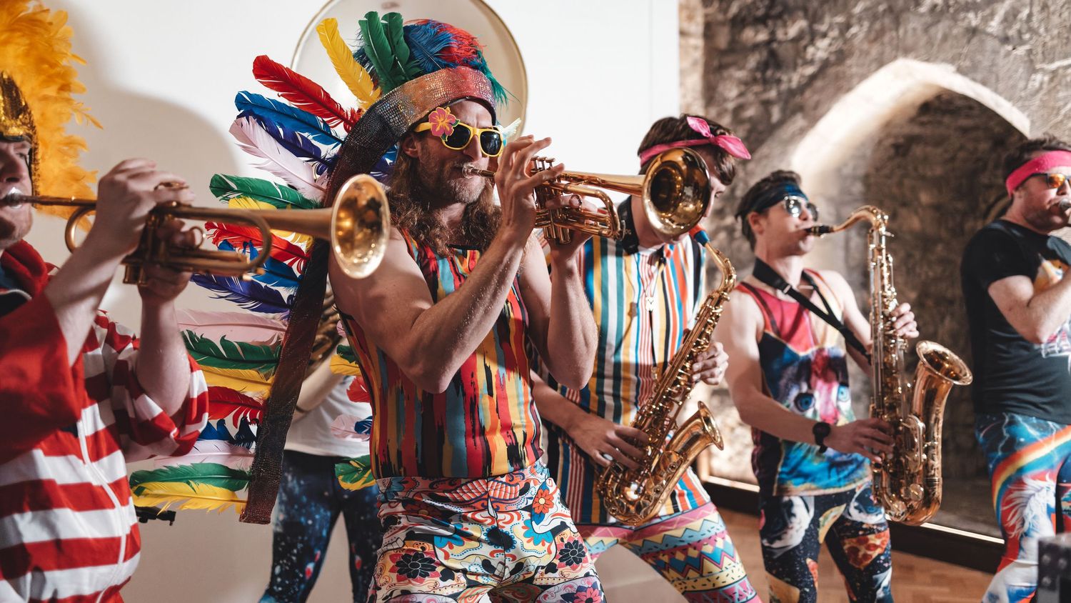 Brass band with trumpets and saxophones performing in colourful outfits at an outdoor festival, live music event photography