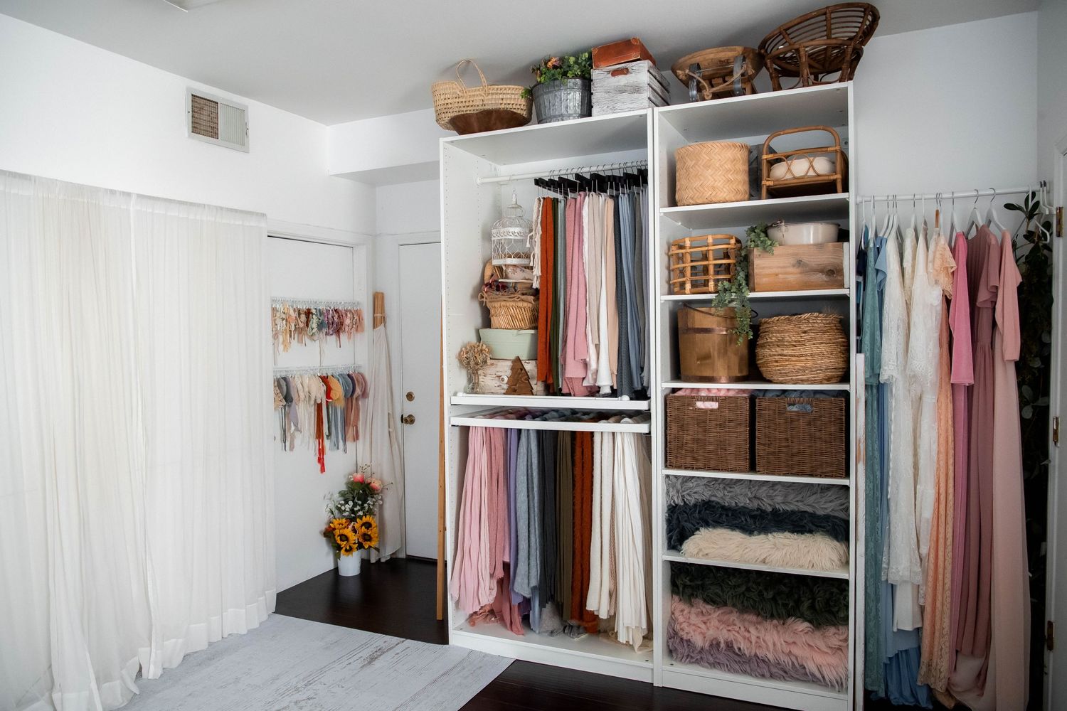 Organized white closet system with hanging clothes and wicker storage baskets.