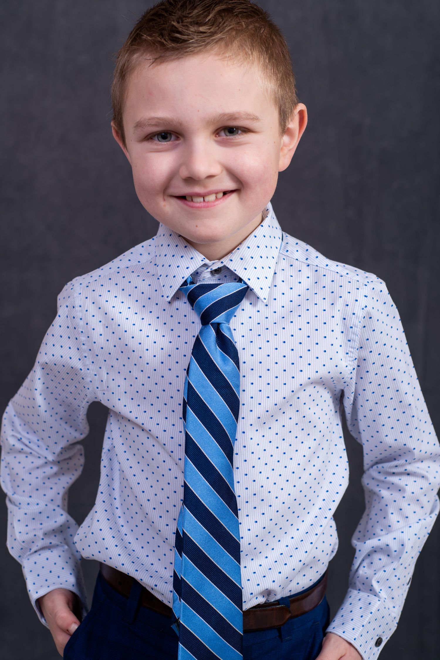 young boy wearing a a blue striped tie, smiling