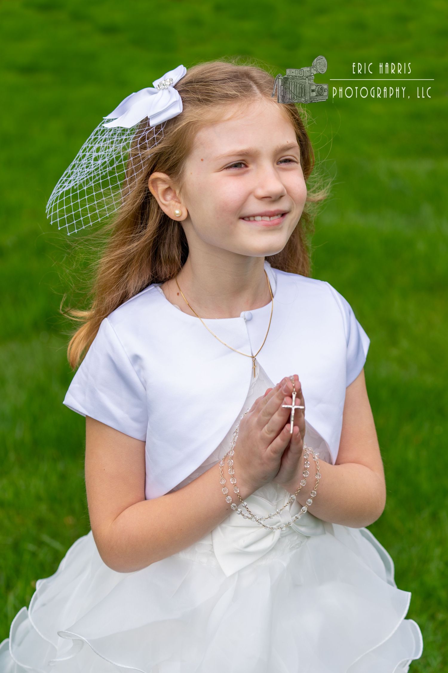 little girl in Communion dress with prayer hands outside