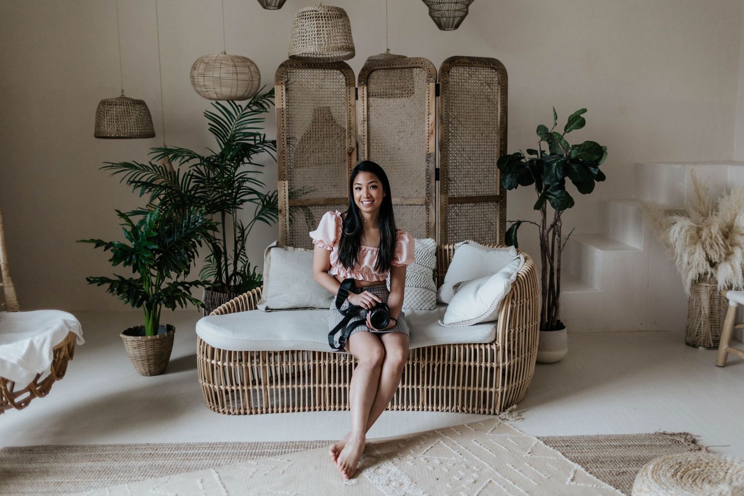 Boho-style living space with wicker furniture, hanging rattan lamps and tropical plants creating a cozy atmosphere.