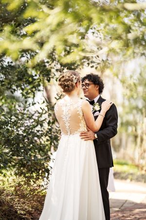 A romantic outdoor wedding portrait showcasing the bride's lace back dress and intimate moment between newlyweds at Elkridge Furnace Inn.