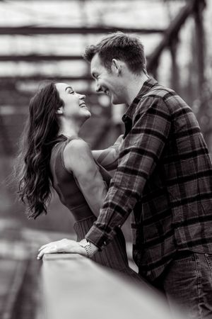 Candid black and white photo of couple laughing together on bridge.