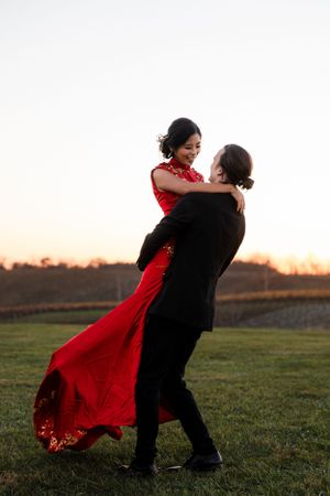A couple shares a romantic dance at sunset, with the woman wearing a flowing red dress.