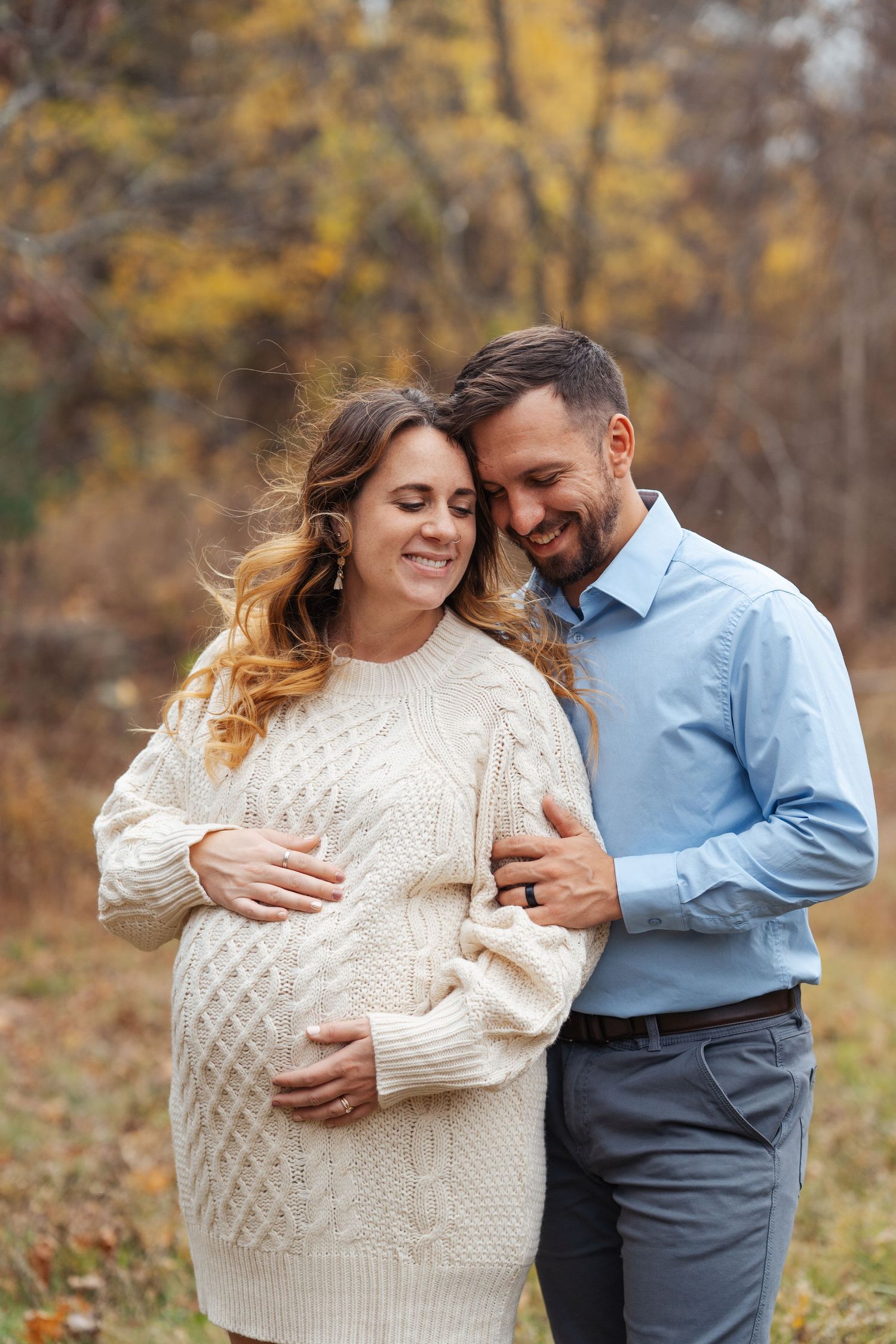 Autumn maternity photo with couple in casual attire.
