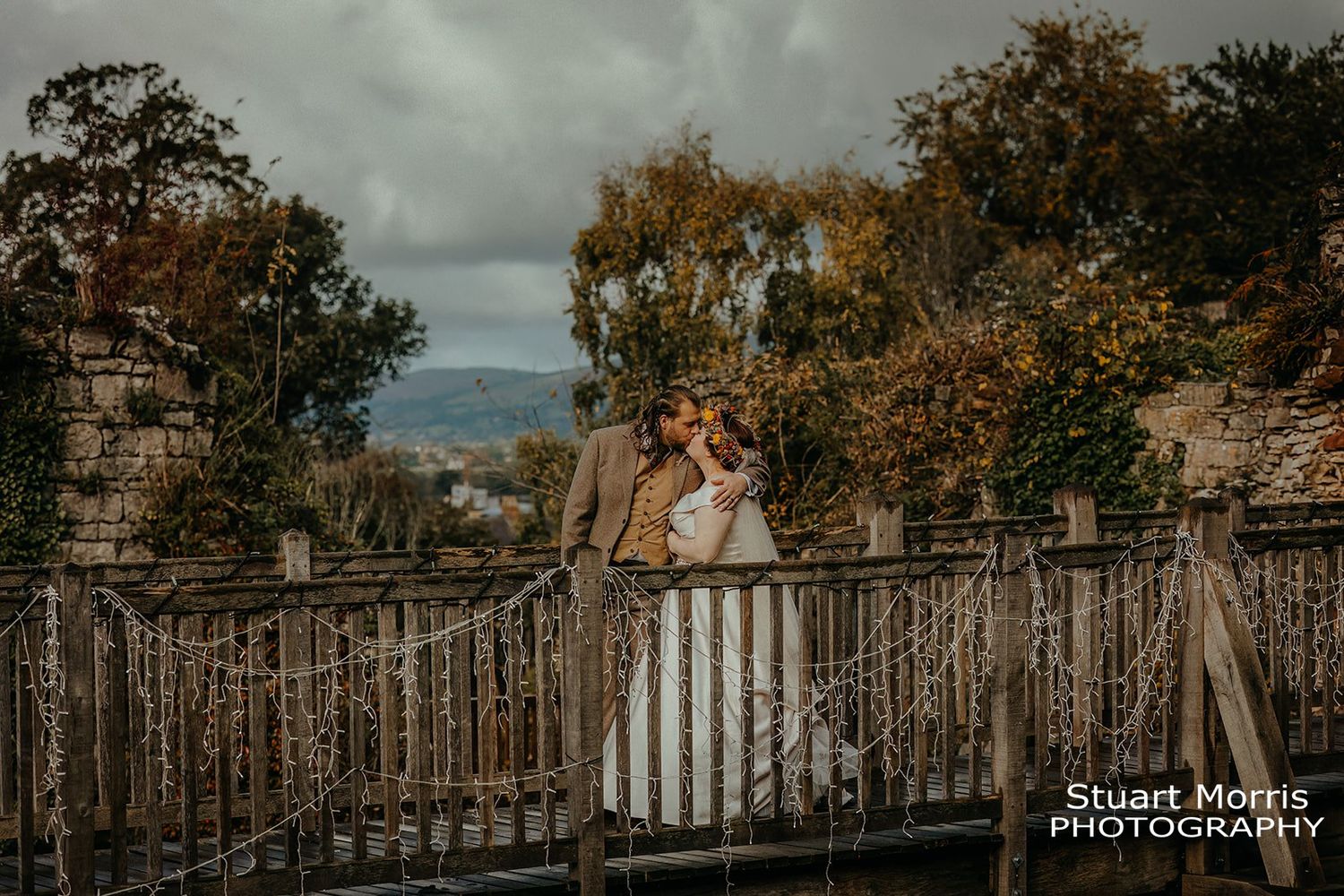 bride and groom kiss on the bridge in the grounds at Ruthin castle north Wales. Stuart Morris Photography.