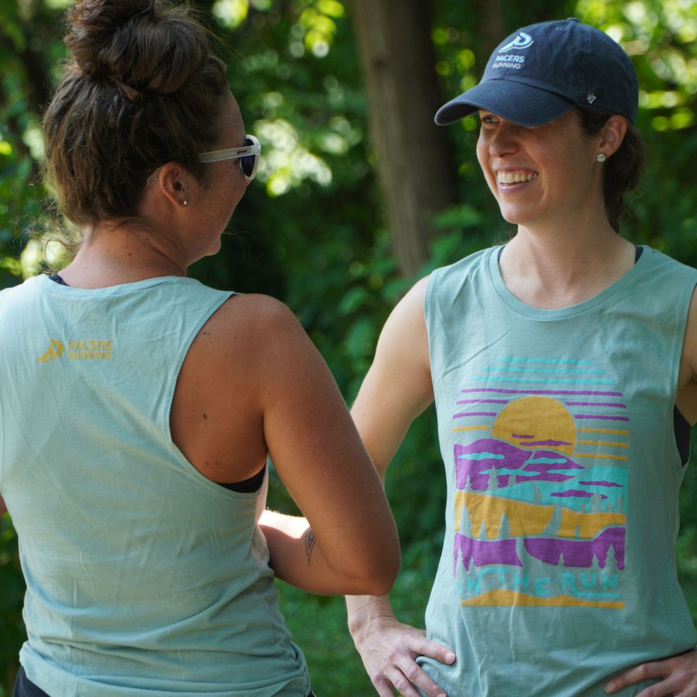 Two athletic tank tops in mint green with colorful sunset graphic designs.