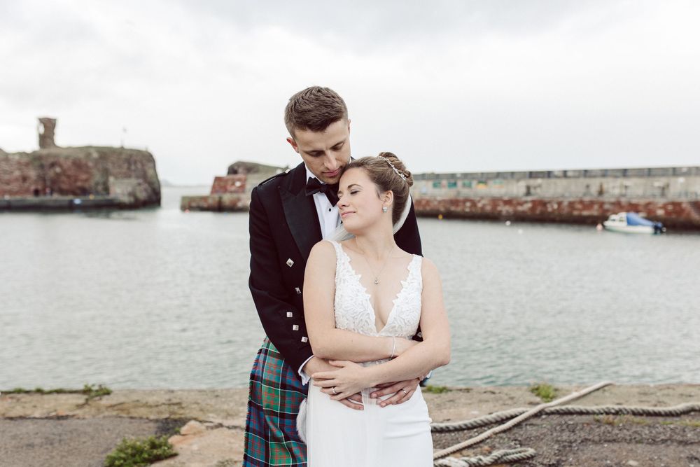Coastal wedding photography session with dramatic cloudy skies and harbor views.