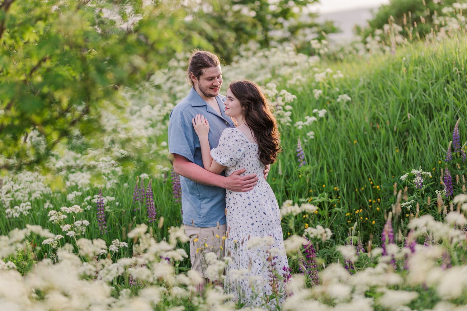 Romantic couple photoshoot in a blooming wildflower meadow during golden hour.