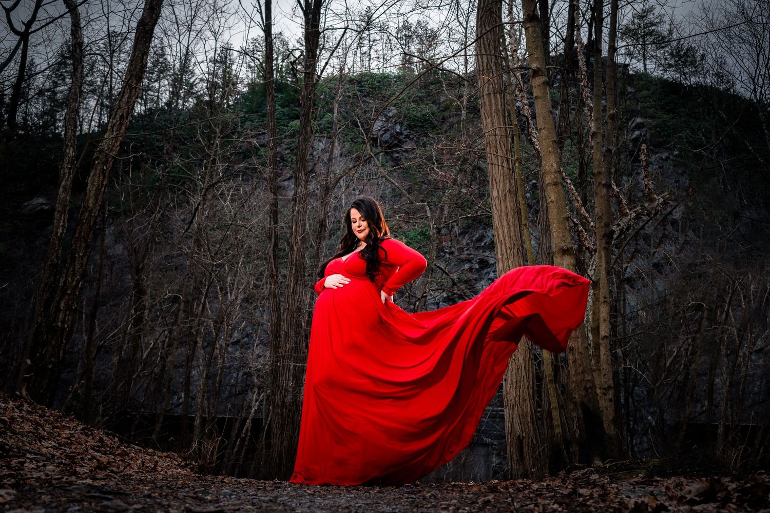 Dramatic forest scene with flowing red fabric against bare winter trees.