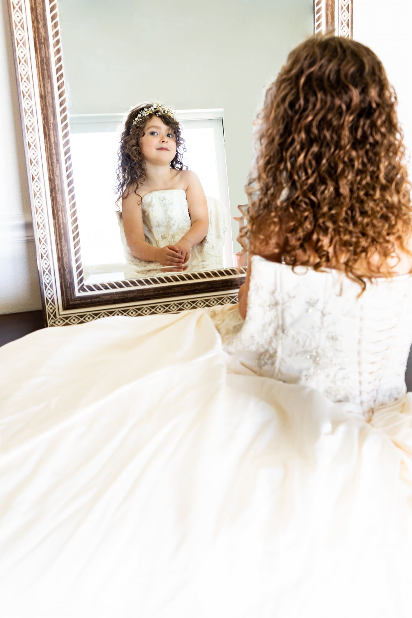 Elopement photo in home in Tampa - little girl in Mom's wedding dress in front of mirror