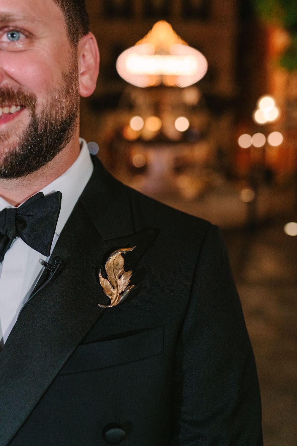 Close-up of formal black tuxedo with gold leaf boutonniere and bow tie.