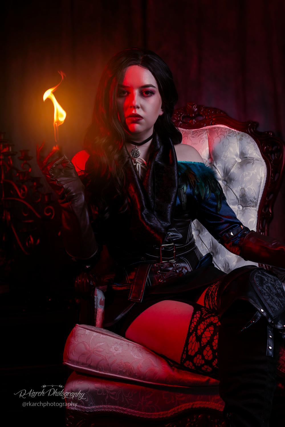 Gothic themed photoshoot with dramatic red lighting and vintage chair.