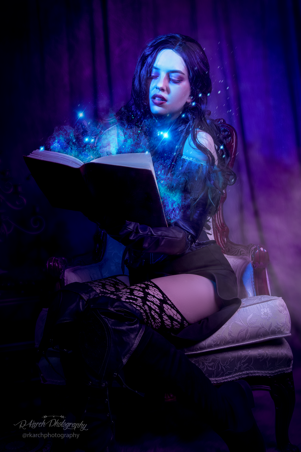 Mystical portrait with figure reading glowing spellbook amid blue magical effects.