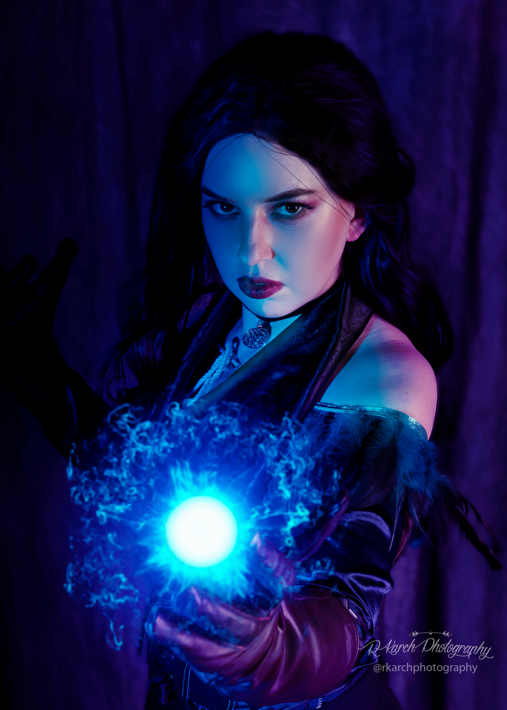 Gothic fantasy portrait with figure wielding bright blue magical orb against purple background.