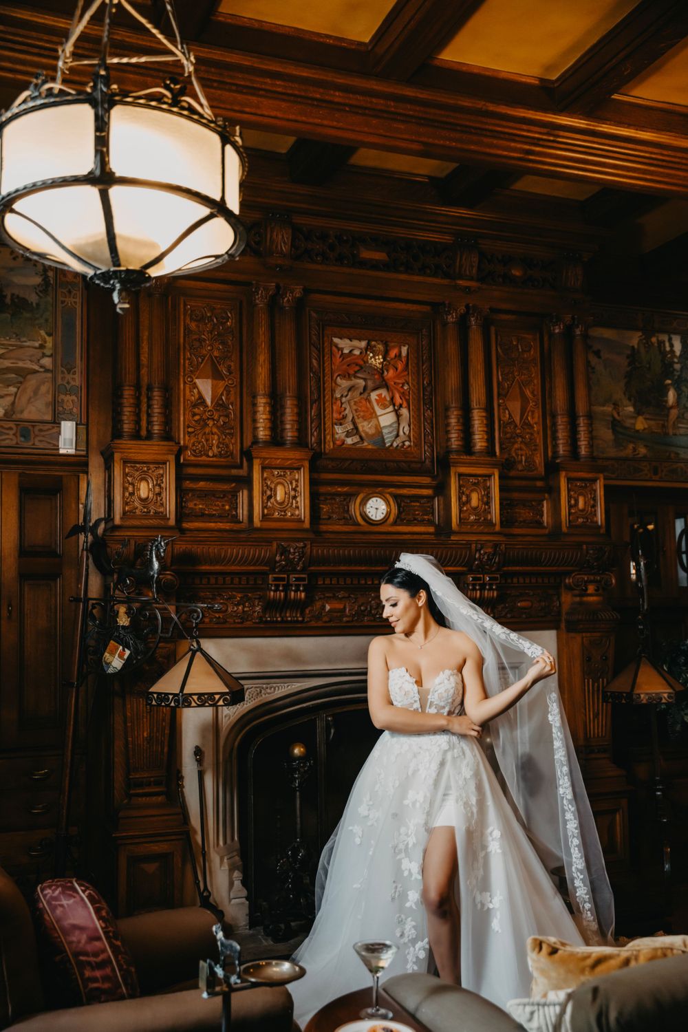 Elegant bridal portrait in vintage room with ornate wooden panels and dramatic lighting.