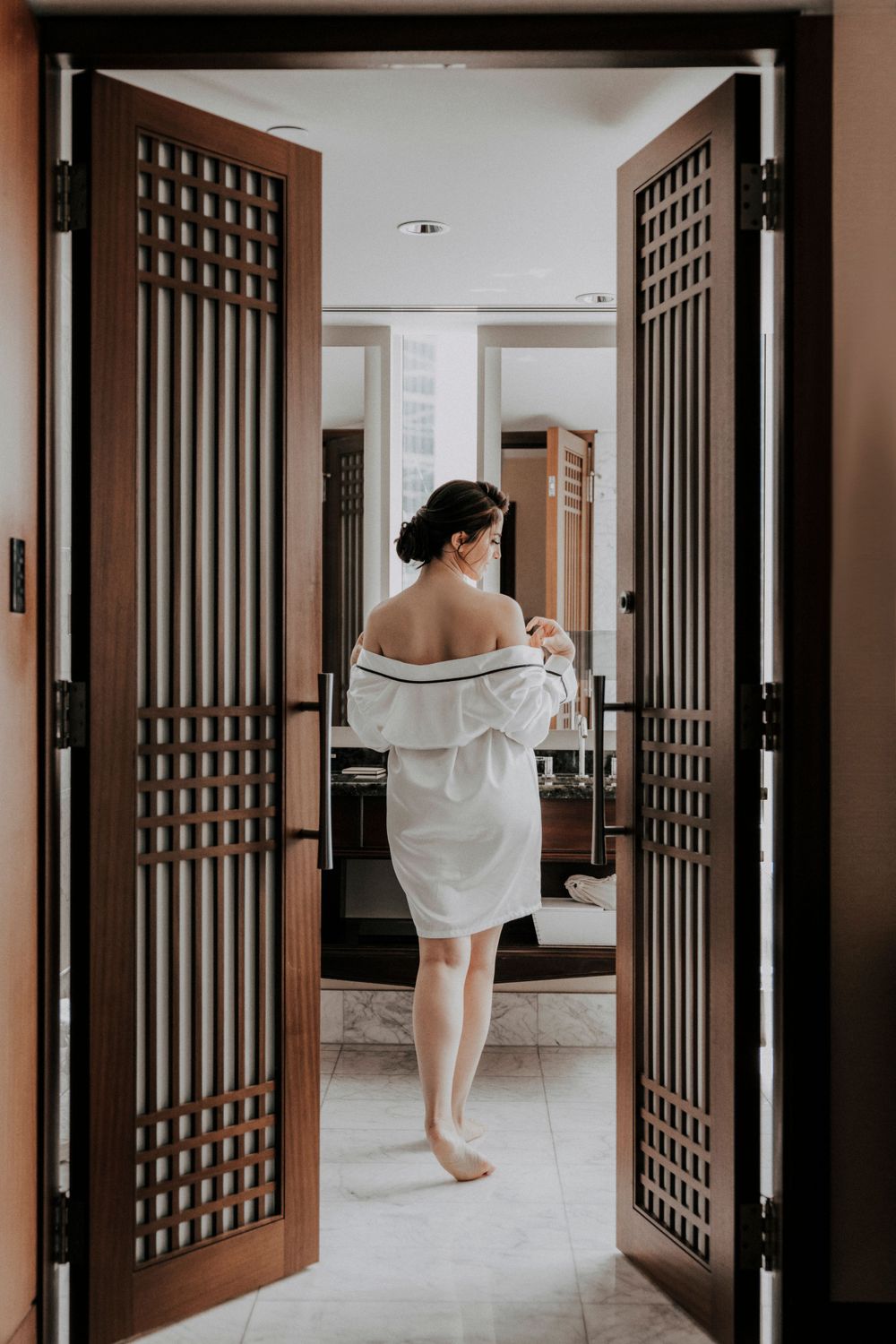 Figure in white robe standing in doorway during wedding preparation morning.