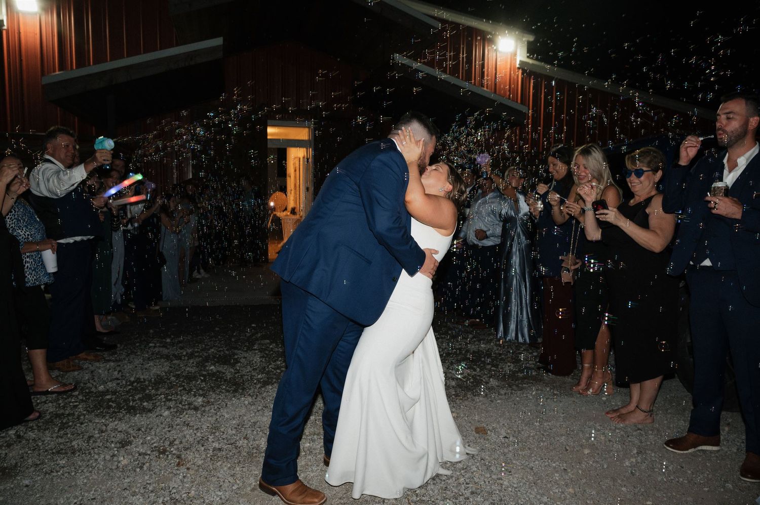 Newlyweds share a romantic moment during sparkler exit surrounded by guests.